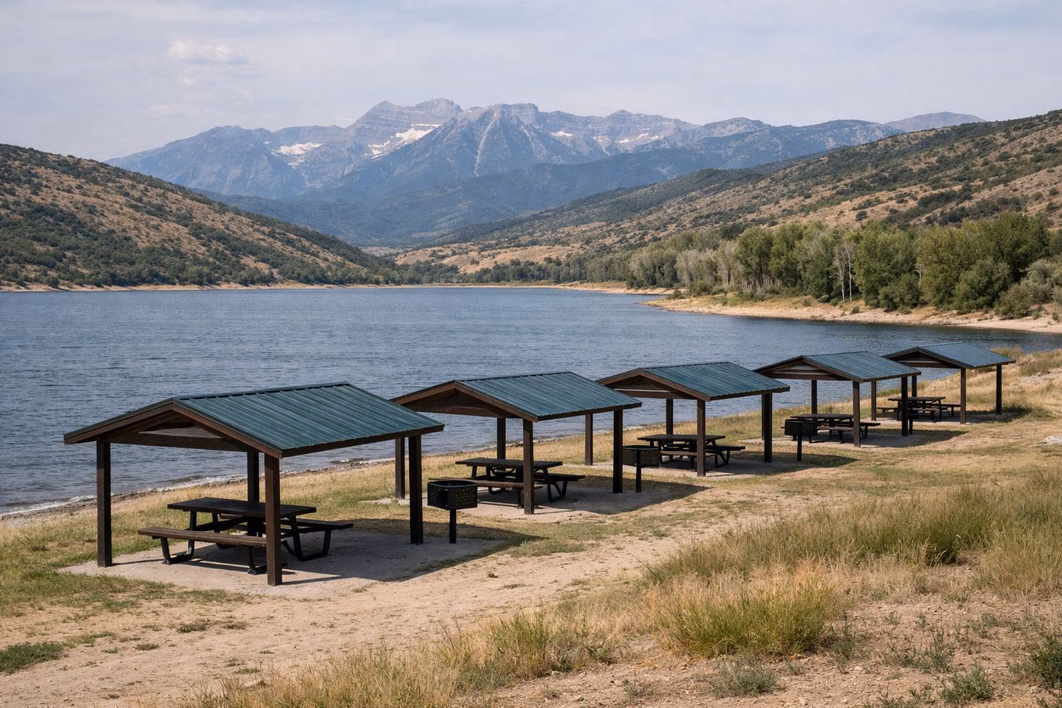 A row of shade cabanas with picnic tables above a reservoir shoreline