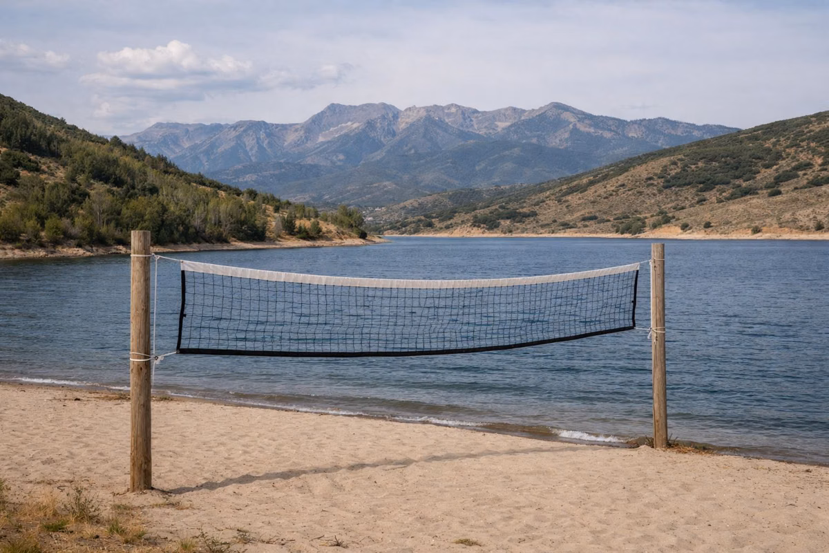 A sand volleyball net on a small beach beside a mountain reservoir